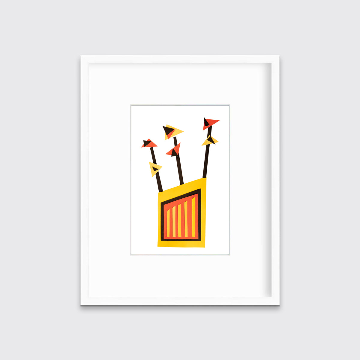 A red, yellow and black abstract collage print in a white frame with a mat hangs on a white wall.