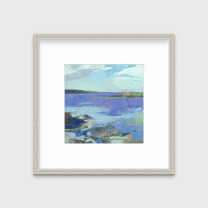 A blue, purple, white and green abstract landscape print in a silver frame with a mat hangs on a white wall.