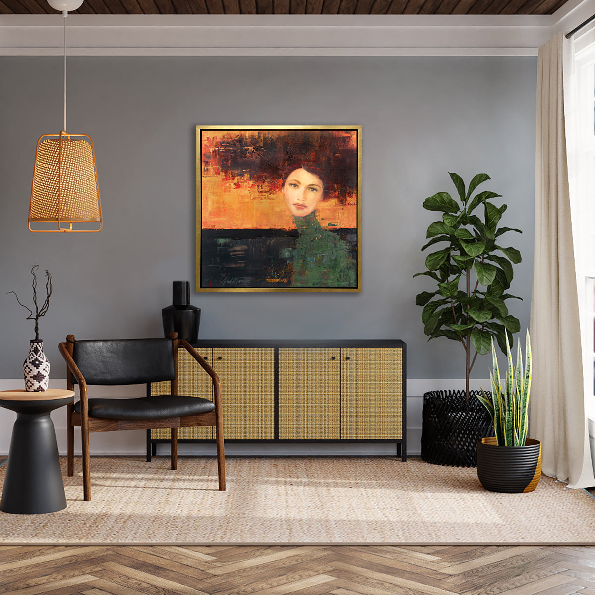 A orange, red, green and black abstract figural print in a gold floater frame hangs on a light grey wall above a black and rattan credenza with a black vase, a black and brown chair, two potted floor plants and a black and wood side table with a vase.