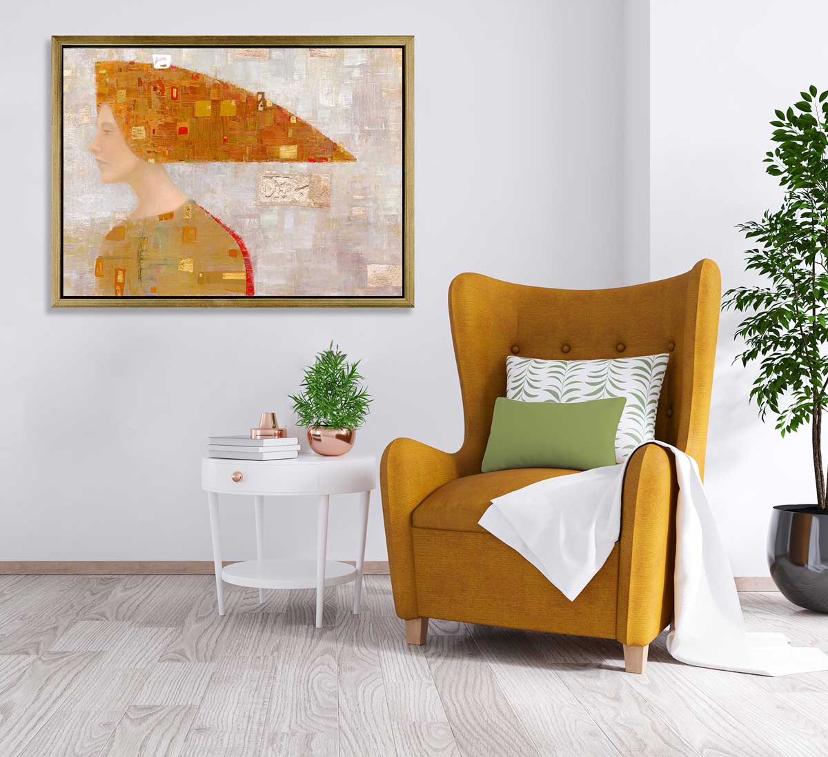 A print of an abstract portrait hangs in a gold floater frame on a white wall to the left of a burnt mustard colored arm chair.