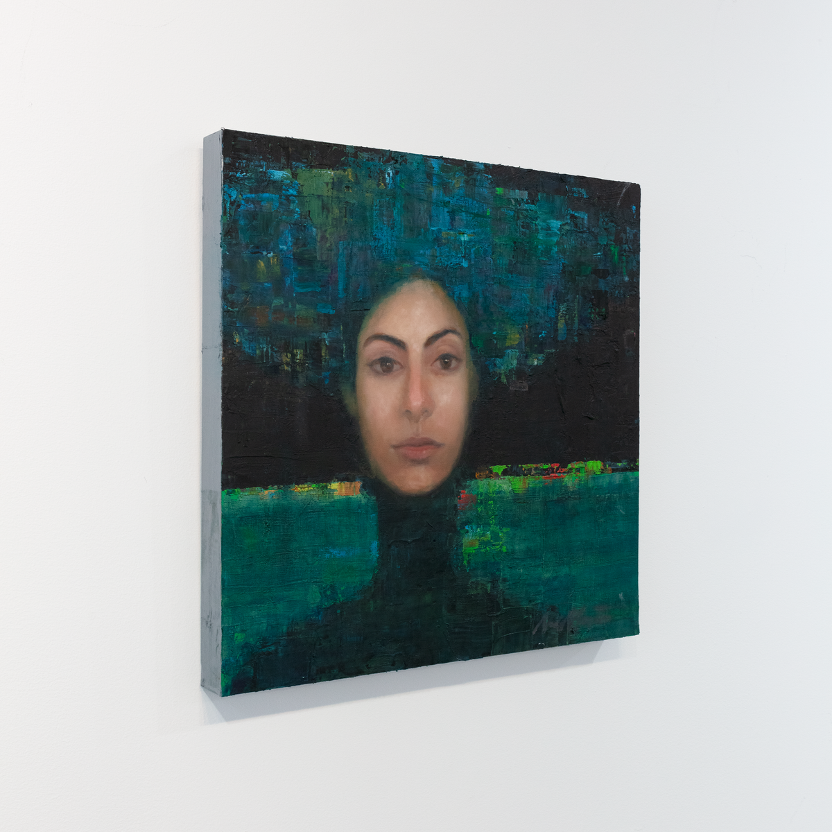 A painting of a woman's face on an abstracted blue and black background is seen at an angle on a gallery wall.