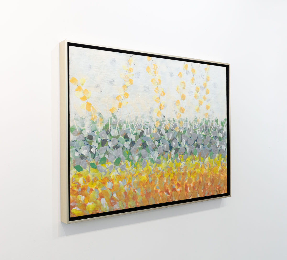 An abstract encaustic painting of gold and silver flowers is seen at an angle on a gallery wall.