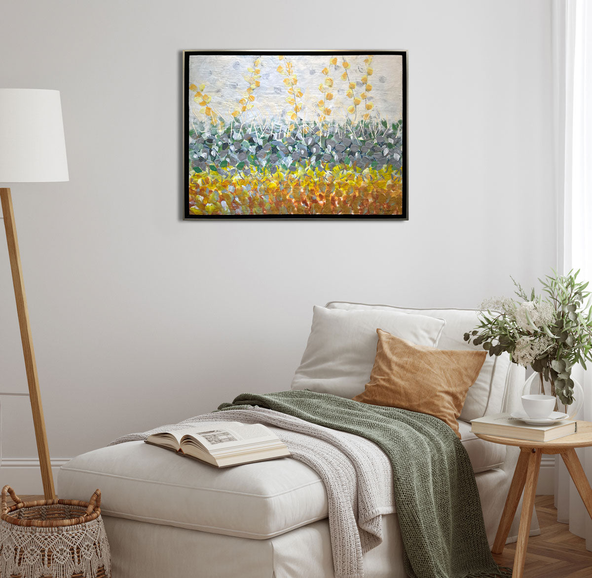 An abstract encaustic painting of gold and silver flowers is hung above an upholstered chair.