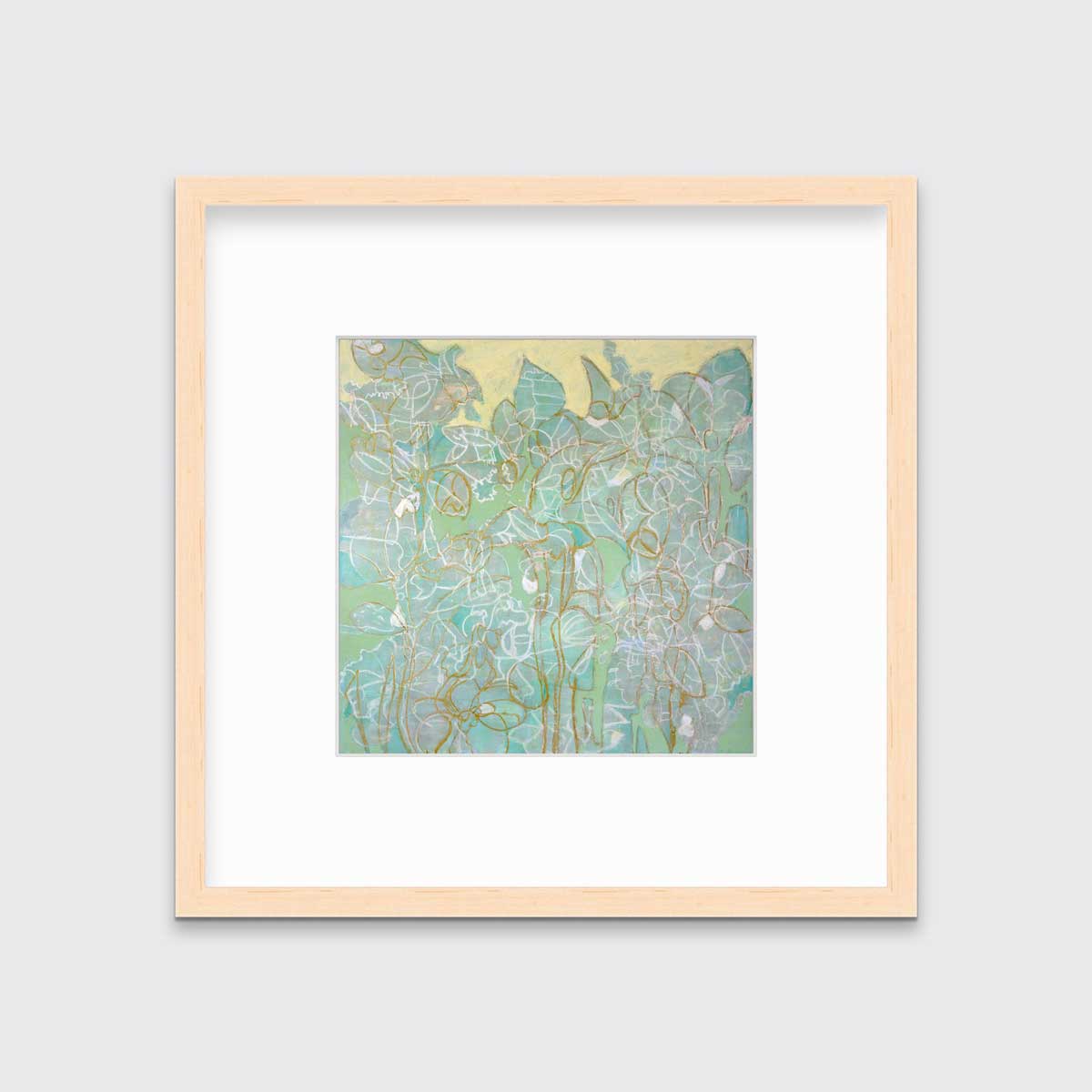 A green, yellow and white abstract print in a natural wood frame with a mat hangs on a white wall.