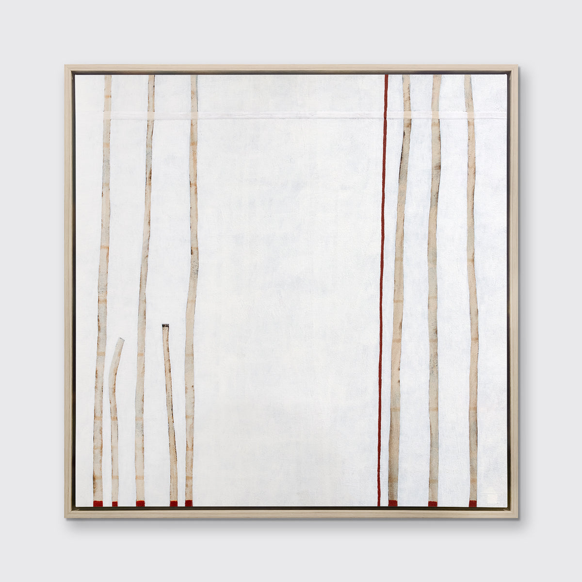 A white, beige and red abstract print in a white oak wood floater frame hangs on a white wall.