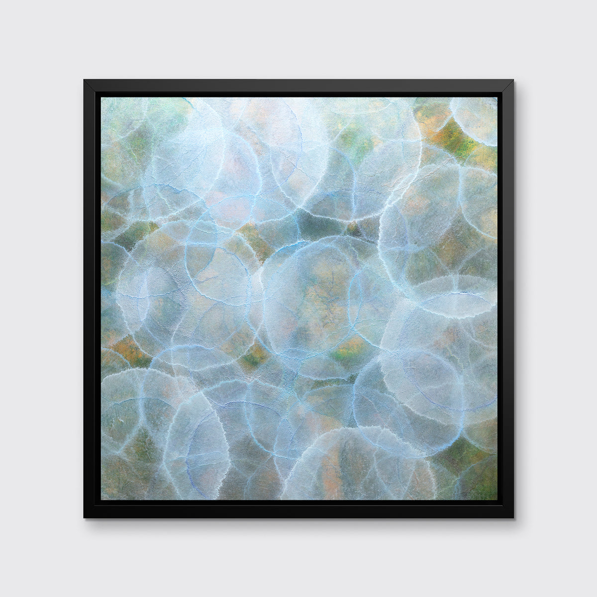 A light blue, green and yellow abstract geometric print in a black floater frame hangs on a white wall.