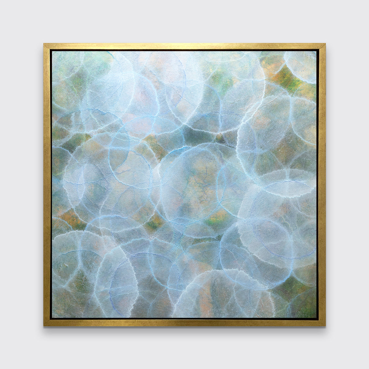 A light blue, green and yellow abstract geometric print in a gold floater frame hangs on a white wall.