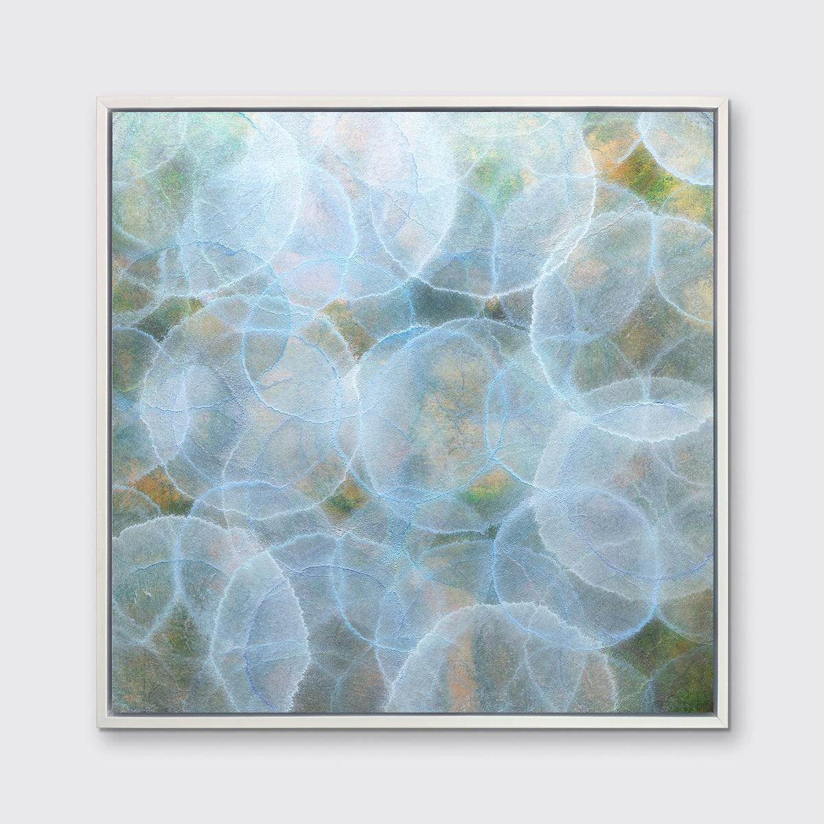 A light blue, green and yellow abstract geometric print in a white floater frame hangs on a white wall.