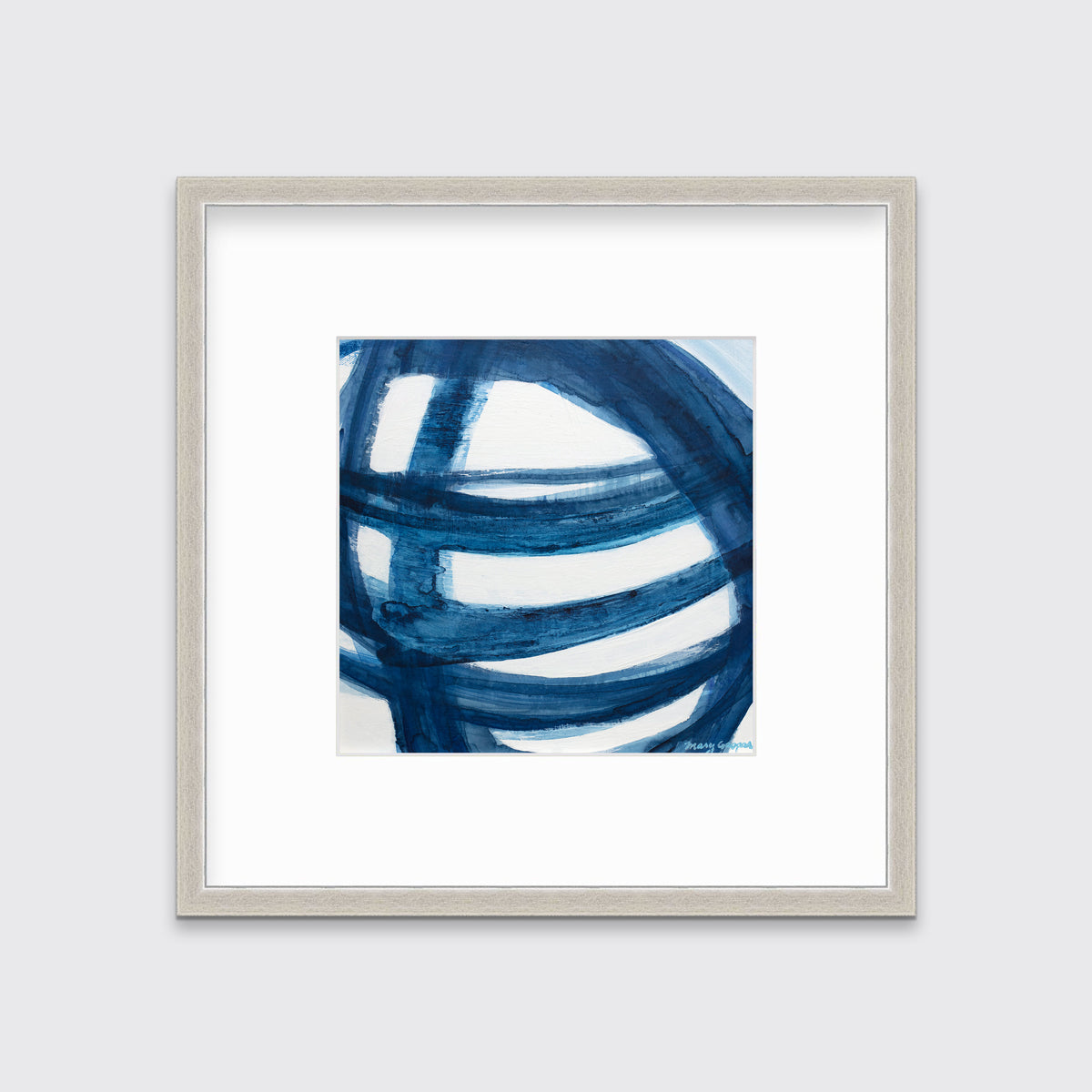 A blue and white abstract print in a silver frame with a mat hangs on a white wall.