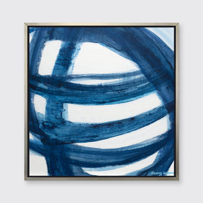 A blue and white abstract print in a silver floater frame hangs on a white wall.