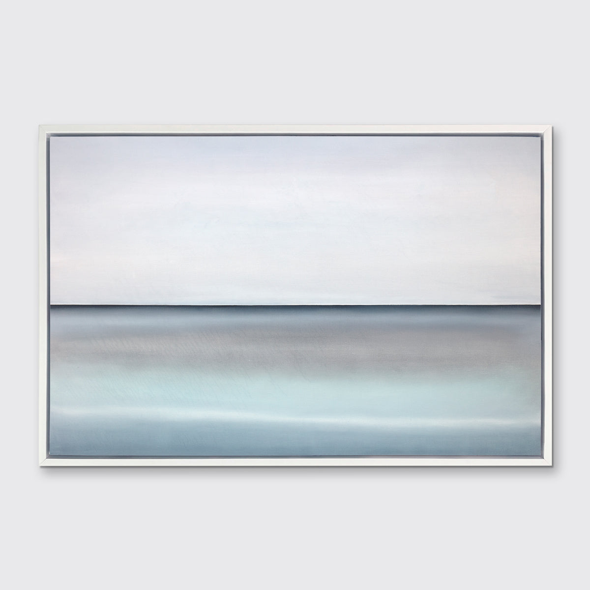 A tonal blue abstract landscape with a defined horizon print in a white floater frame hangs on a white wall.
