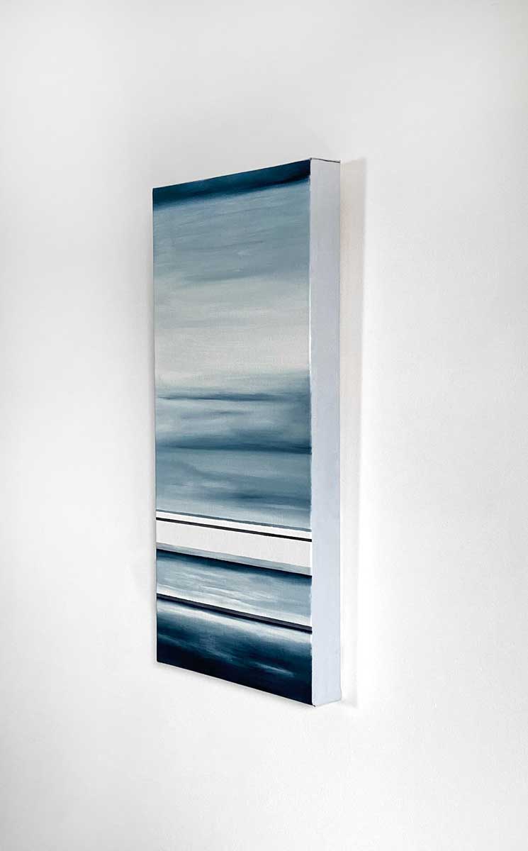 Side angle view of different sized bands of hues of blue and white hanging on a white wall.