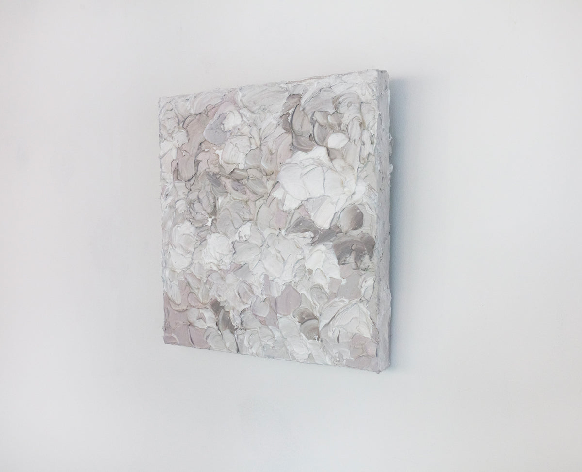 A right angle view of a small abstract painting by Teodora Guererra. It hangs on a white gallery wall.