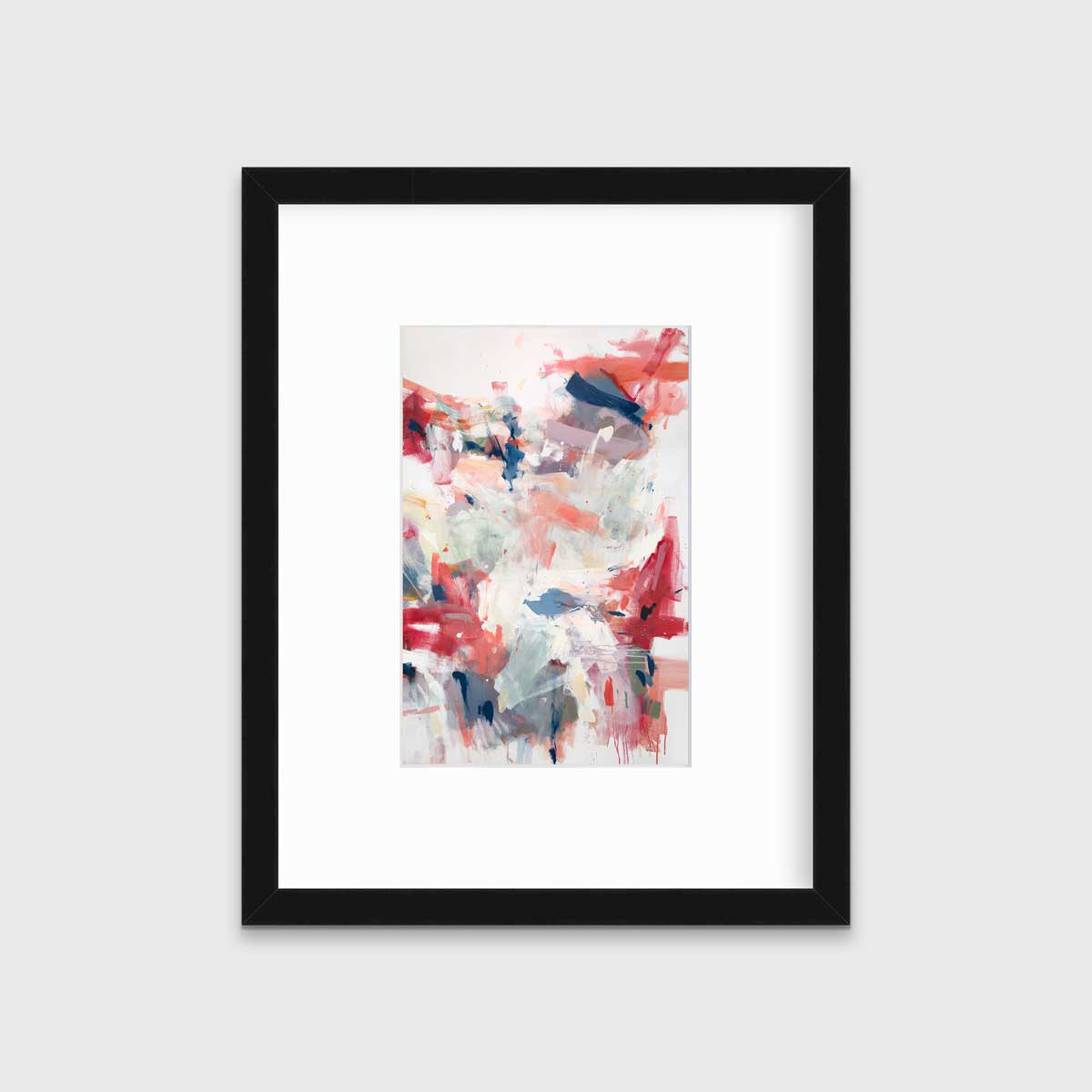 A red and white abstract print in a black frame with a mat hangs on a white wall.