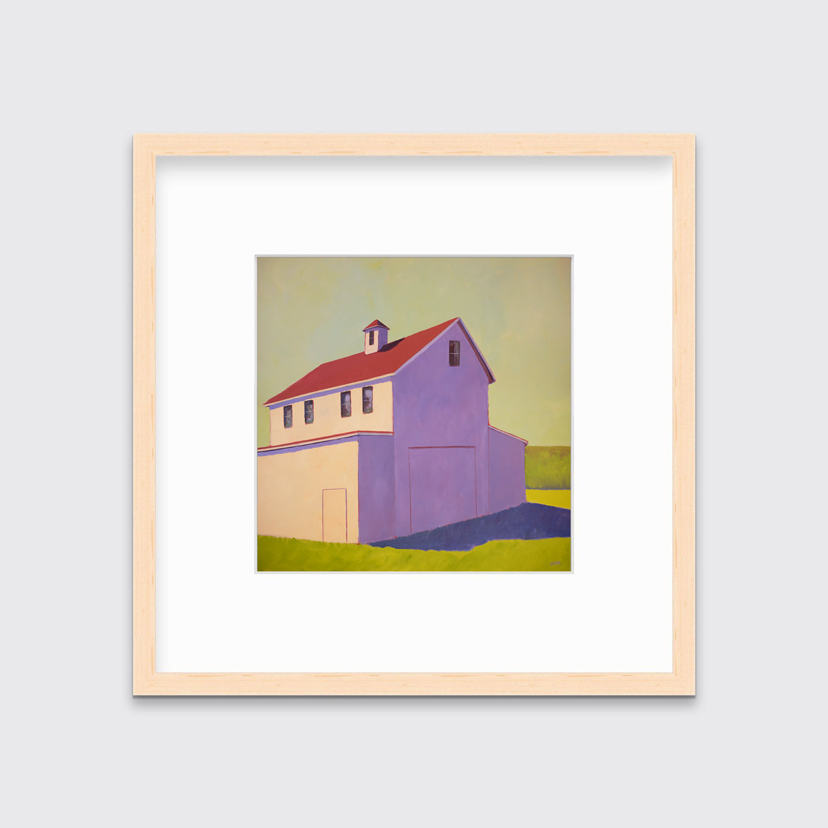 A contemporary barn print in a natural wood frame with a mat hangs on a white wall.