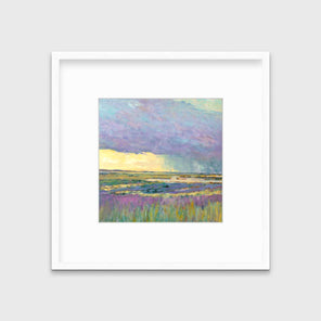 A multicolored abstract landscape print in a white frame with a mat hangs on a white wall.