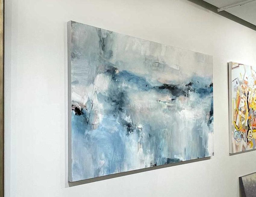 Cool toned abstract painting with spots of beige by Kelly Rossetti hangs on a white wall in the gallery, viewed from the left. 