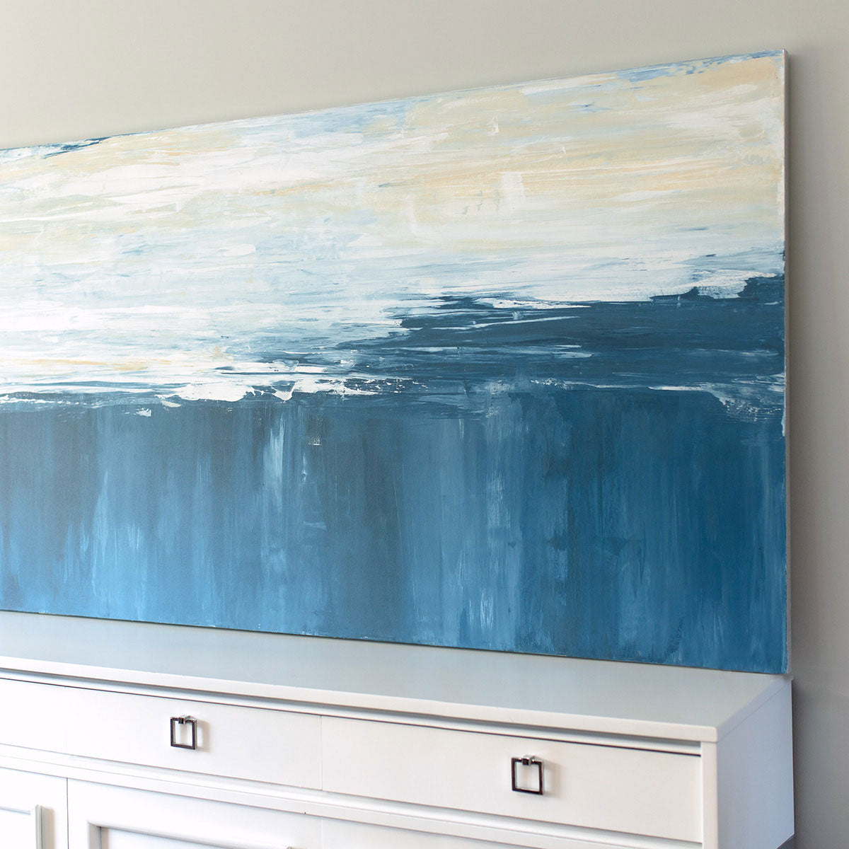 A side angle view of an abstract painting of blue and white forms converging.