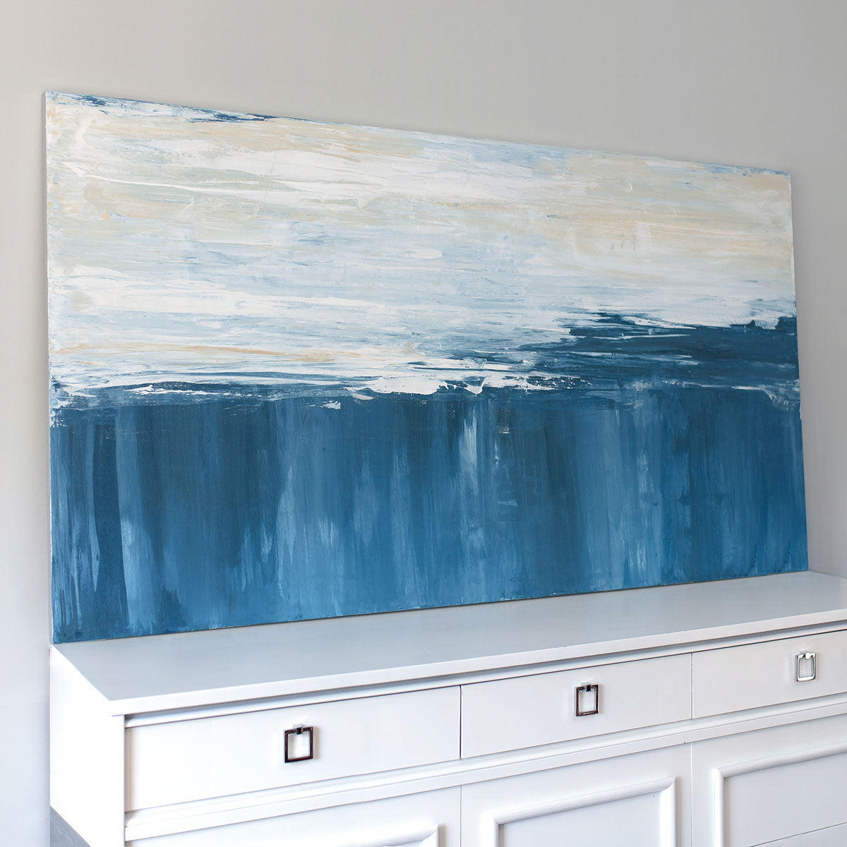 A side angle view of an abstract painting of blue and white forms converging.