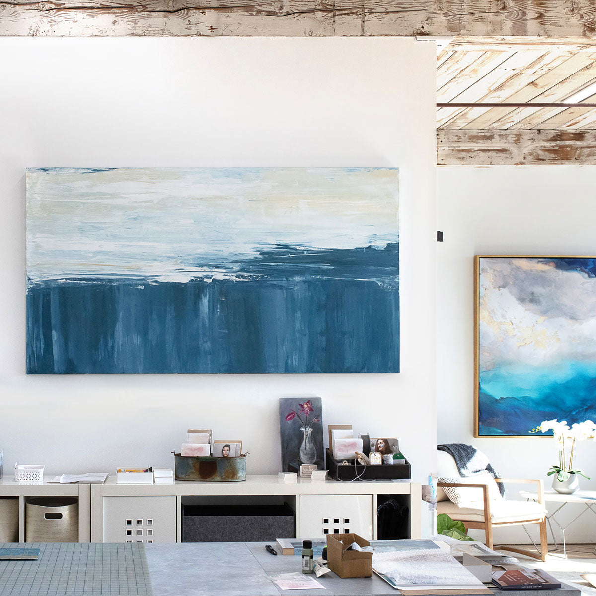 An abstract painting of blue and white forms converging is hung in a living space.