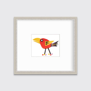A red bird collage in a silver frame with a mat hangs on a white wall.