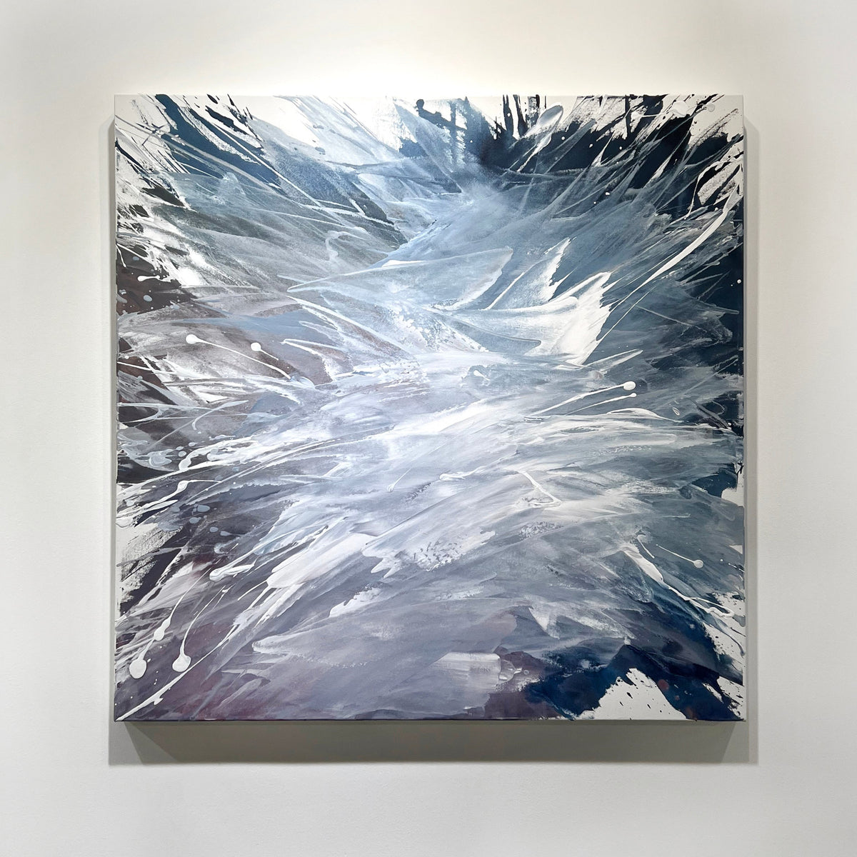 A white, blue, and lavender abstract painting by Teodora Guererra hangs on a white wall. 