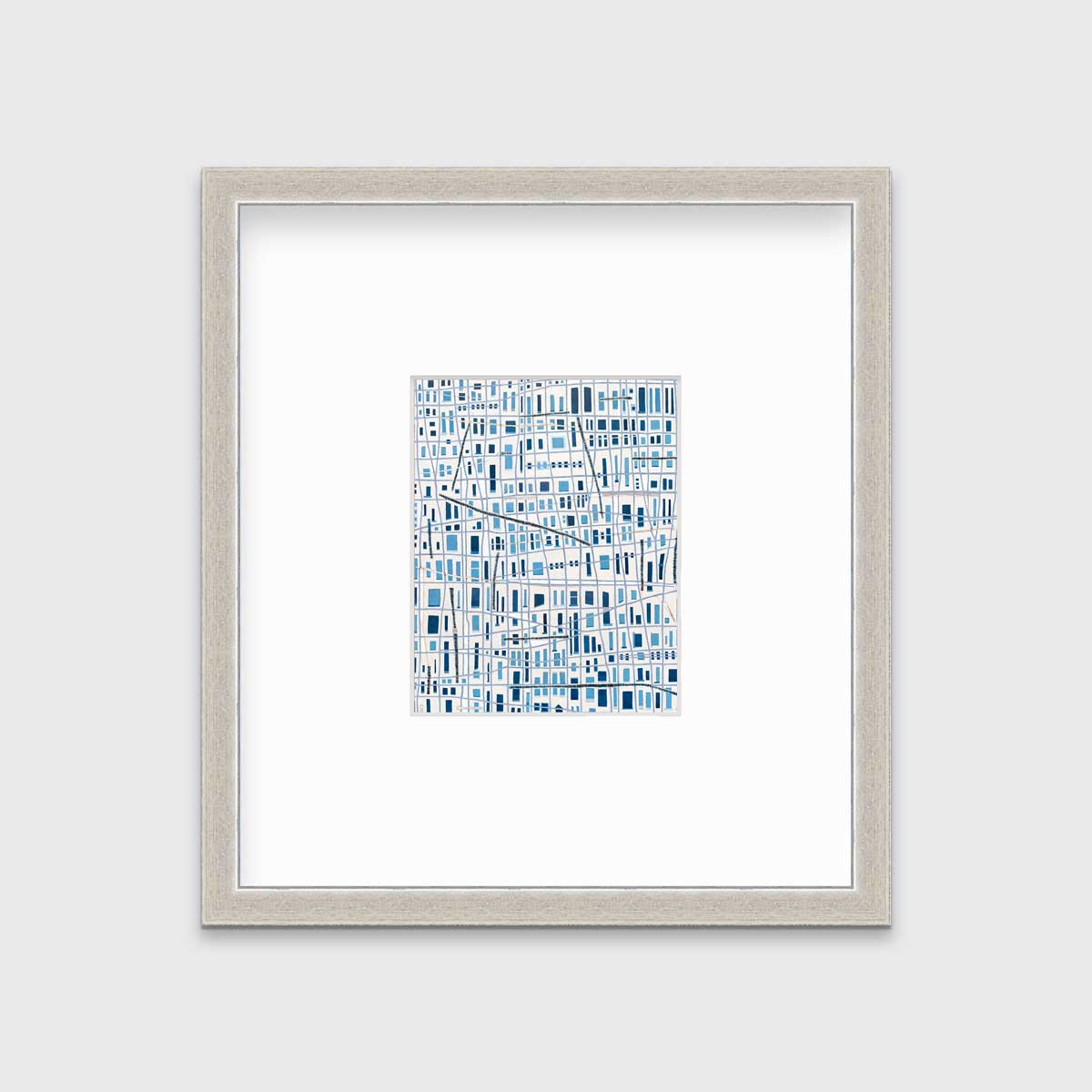 A blue and white geometric abstract print in a silver frame with a mat hangs on a white wall.