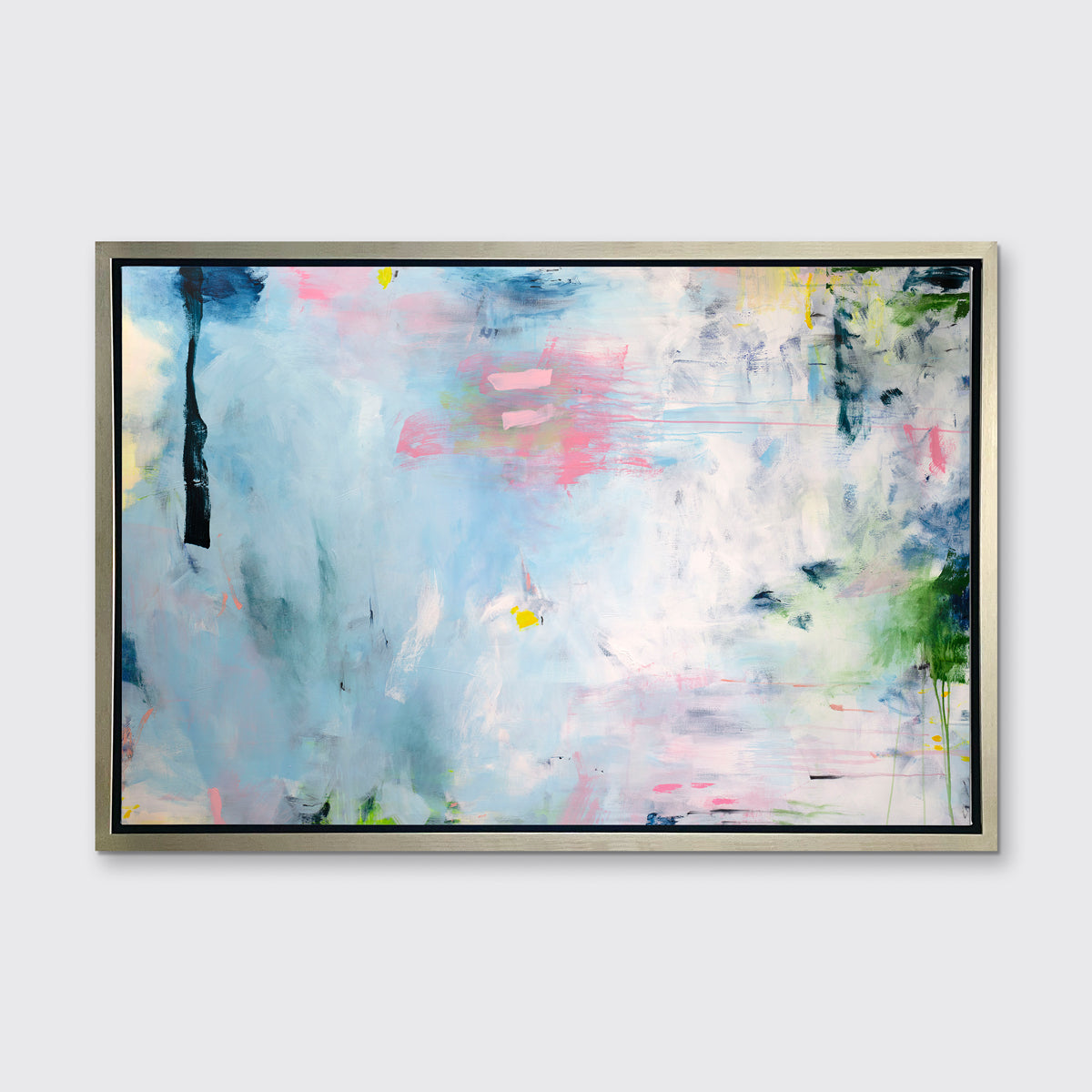 A blue, pink and white abstract print in a silver floater frame hangs on a white wall.