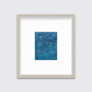 A dark teal abstract print in a silver frame with a mat hangs on a white wall.