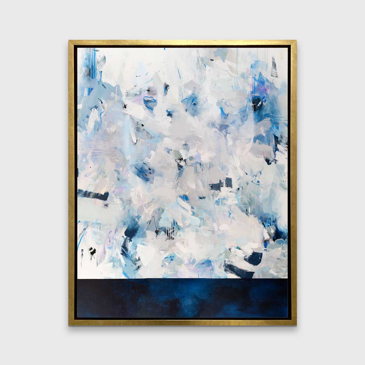A blue, white and light grey abstract print in a gold floater frame hangs vertically on a white wall.