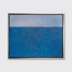 A deep blue abstract landscape print in a silver floater frame hangs on a white wall.