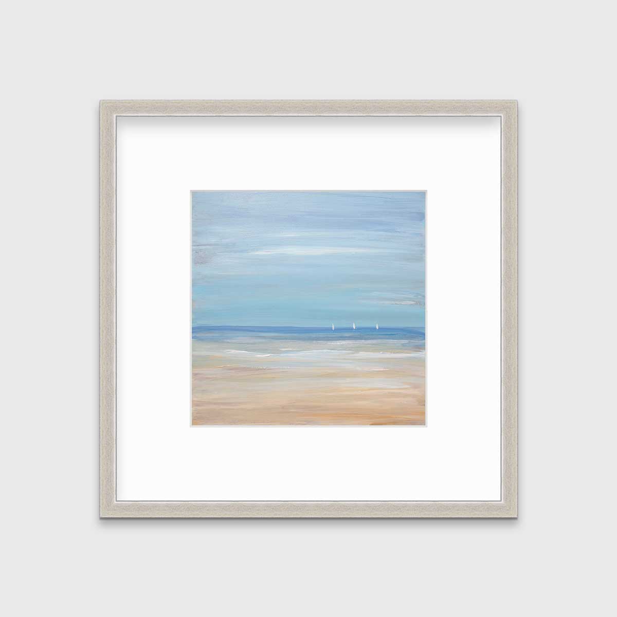 A blue, beige and white abstract seascape print with three small sailboats in a silver frame with a mat hangs on a white wall.