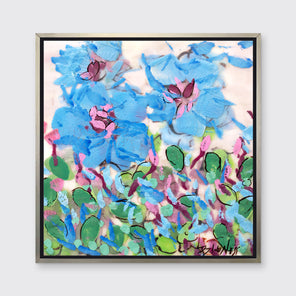 A blue, pink, green and white abstract floral print in a silver floater frame hangs on a white wall.