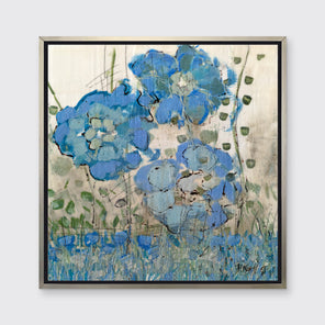 A blue and beige floral print in a silver floater frame hangs on a white wall.