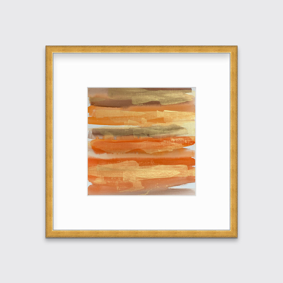 A gold, orange and light brown abstract print in a gold frame with a mat hangs on a white wall.