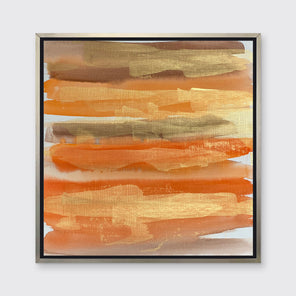 A gold, orange and light brown abstract print in a silver floater frame hangs on a white wall.