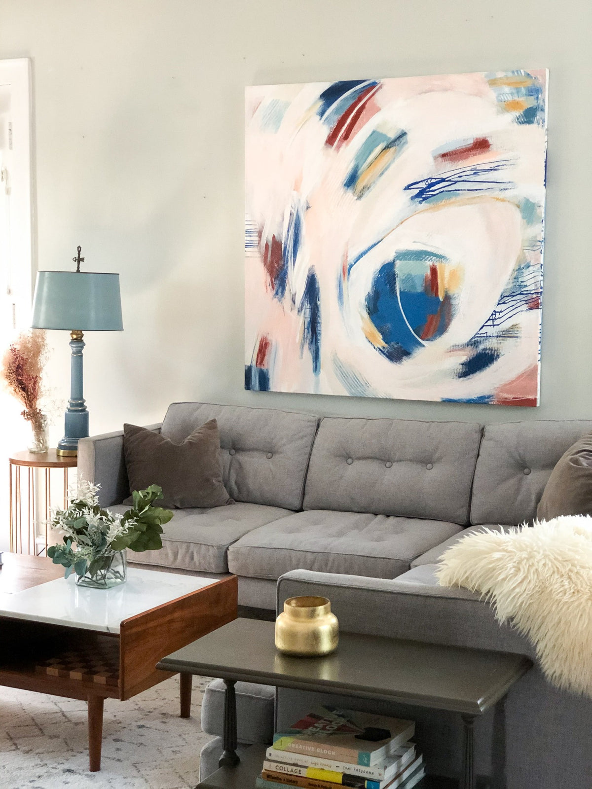 Mary Gaspar's painting, Touch, hanging on a light grey wall above a grey sectional. 