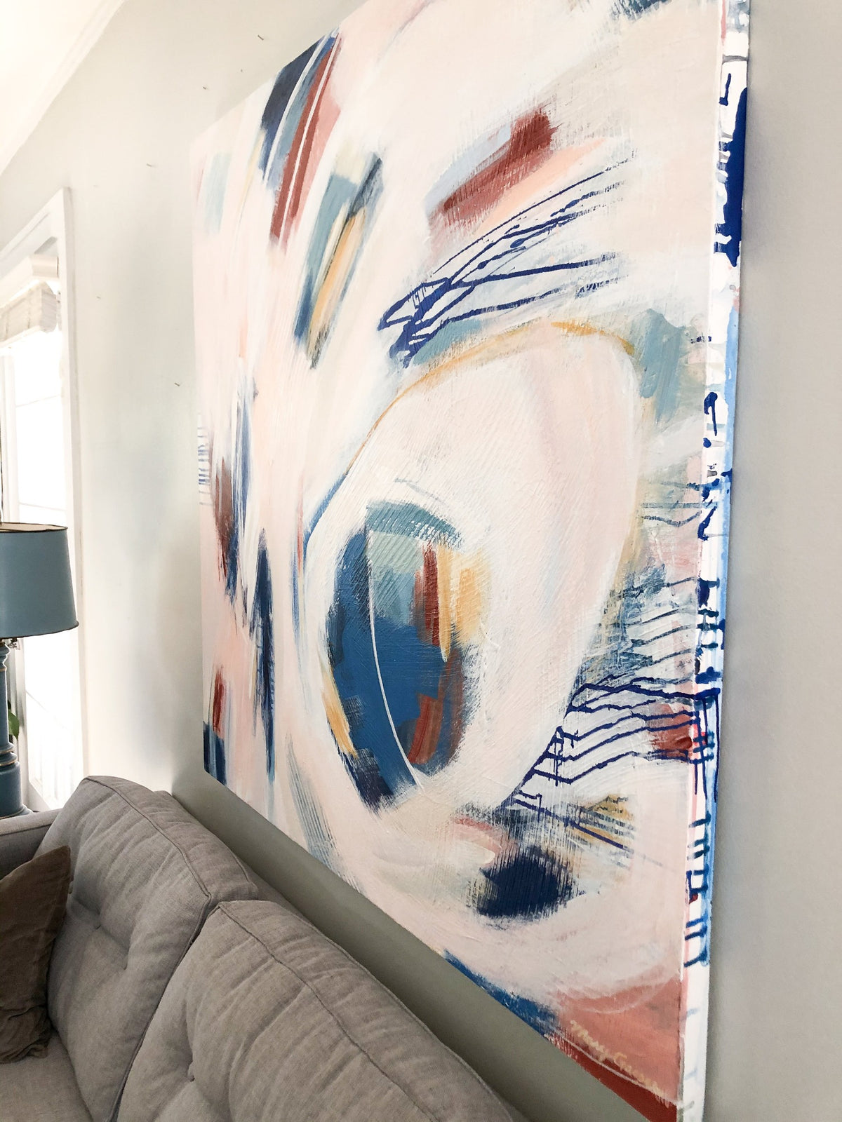 A close up from the right of Mary Gaspar's painting, Touch, hanging on a light grey wall above a grey sectional.