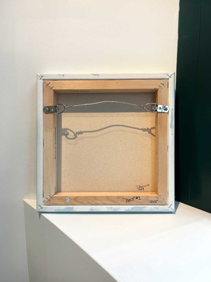 The back of the painting sits on a white surface.