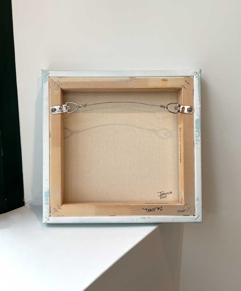 The back of the painting, sits on a white surface.