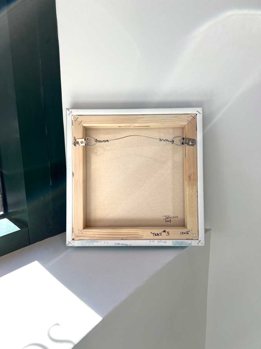 The back of the painting, sits on a white surface.