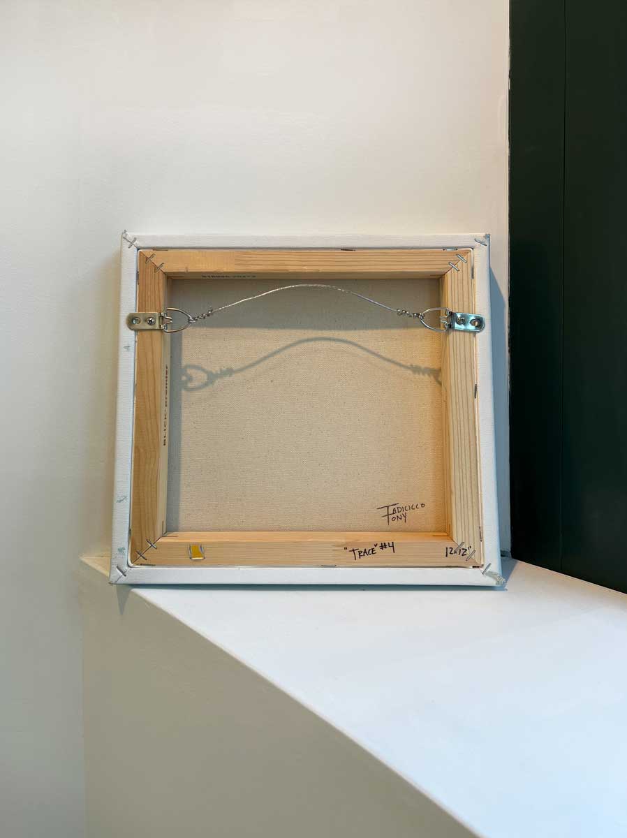 The back of the painting, sits on a white surface.
