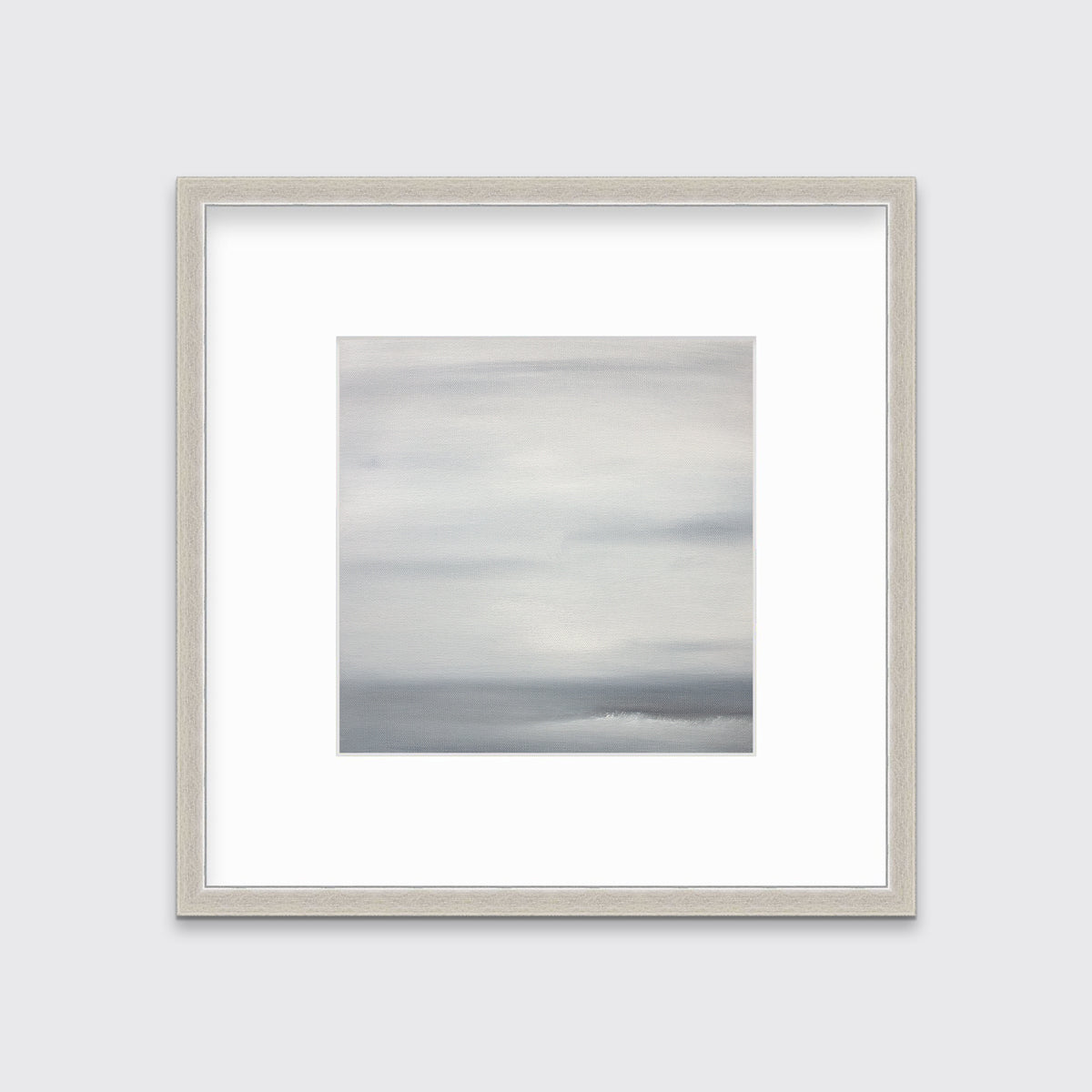 A tonal grey print in a silver frame with a mat hangs on a white wall.