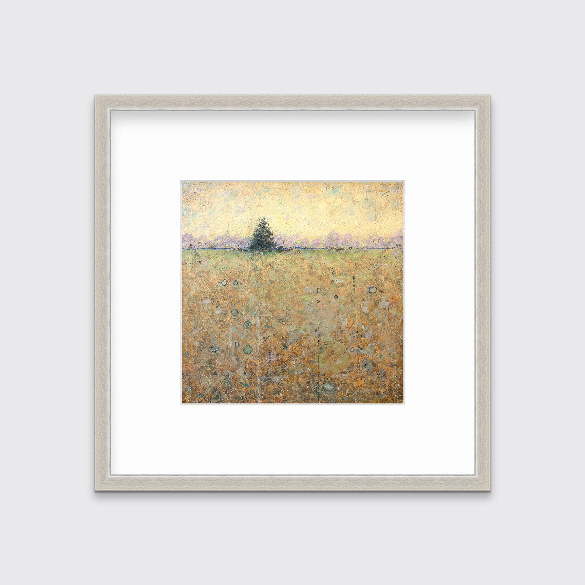 A green, orange and yellow abstract landscape print in a silver frame with a mat hangs on a white wall.