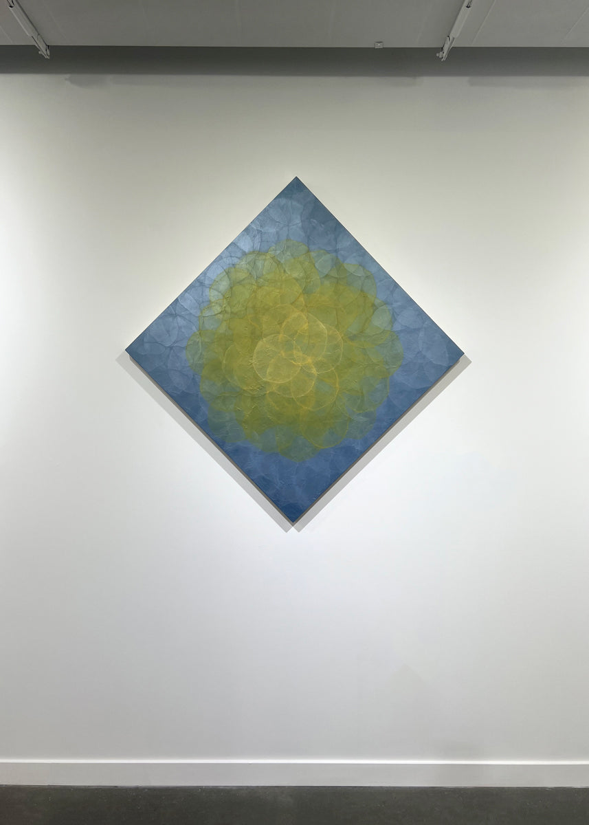 A blue and yellow abstract geometric painting hung on a white wall.