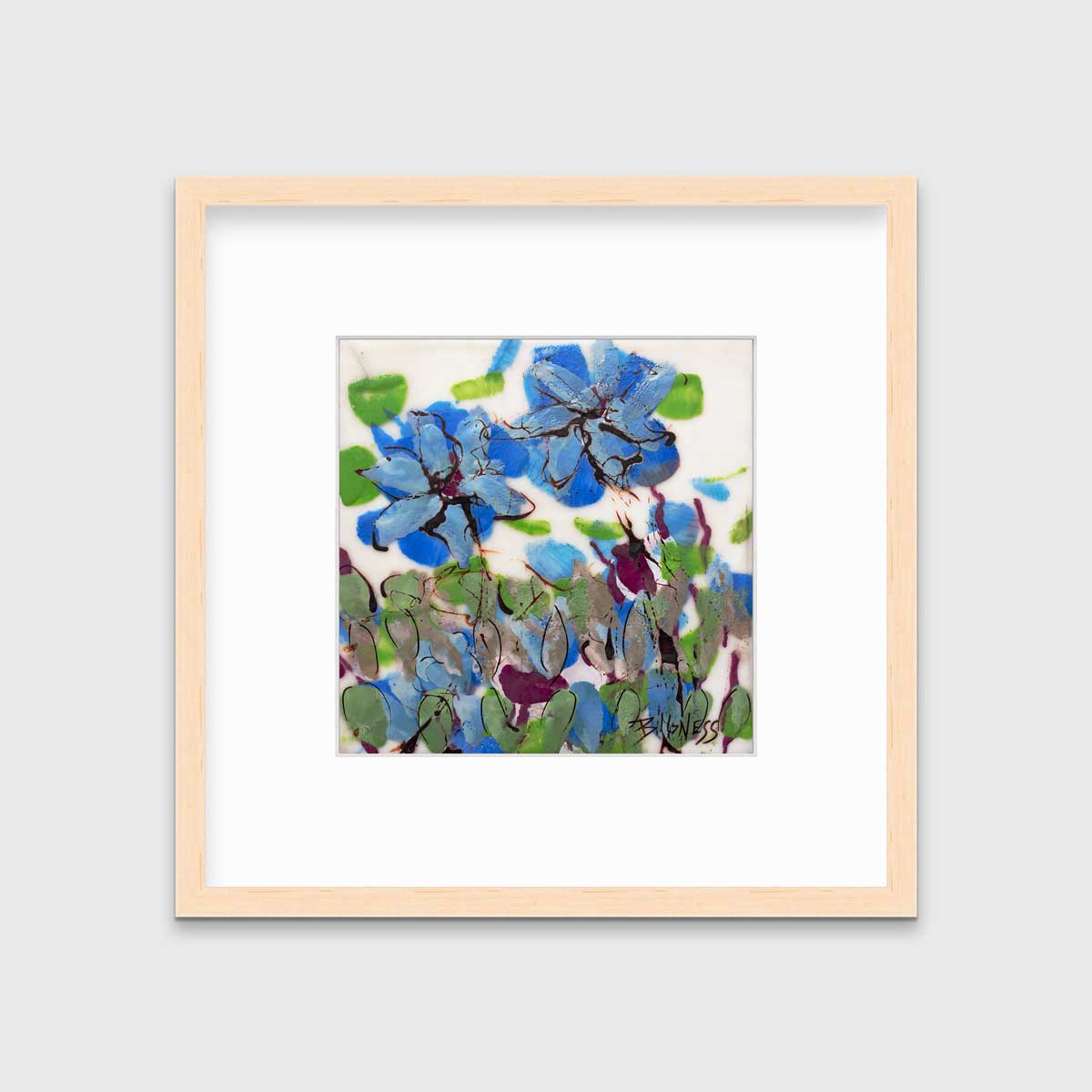 A blue, green and white abstract floral print in a natural wood frame with a mat hangs on a white wall.