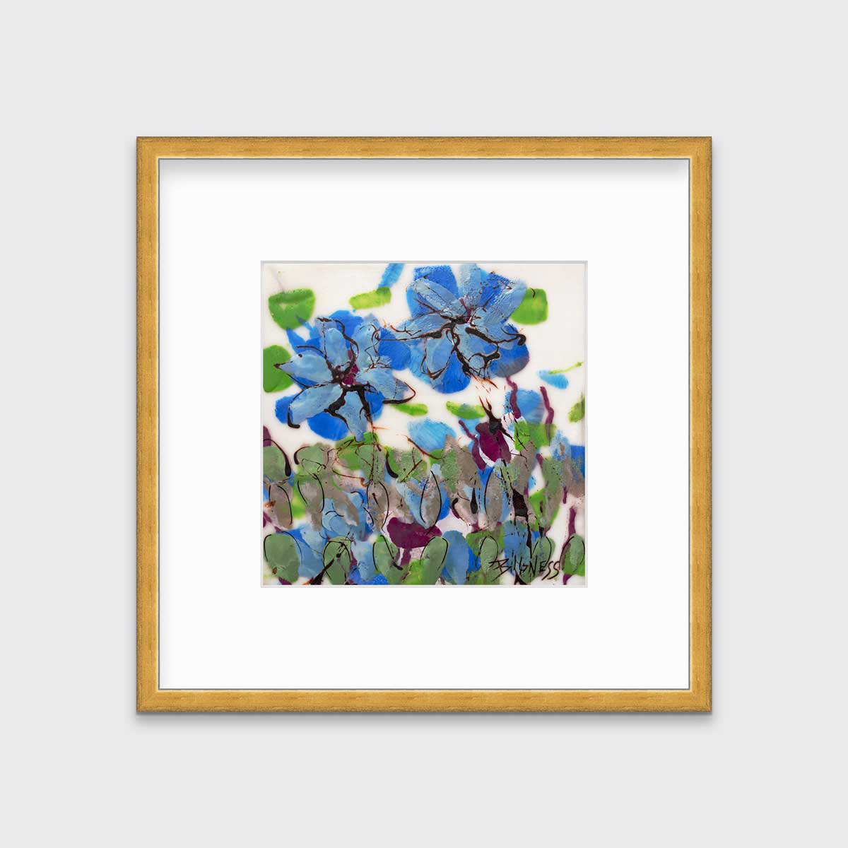 A blue, green and white abstract floral print in a gold frame with a mat hangs on a white wall.