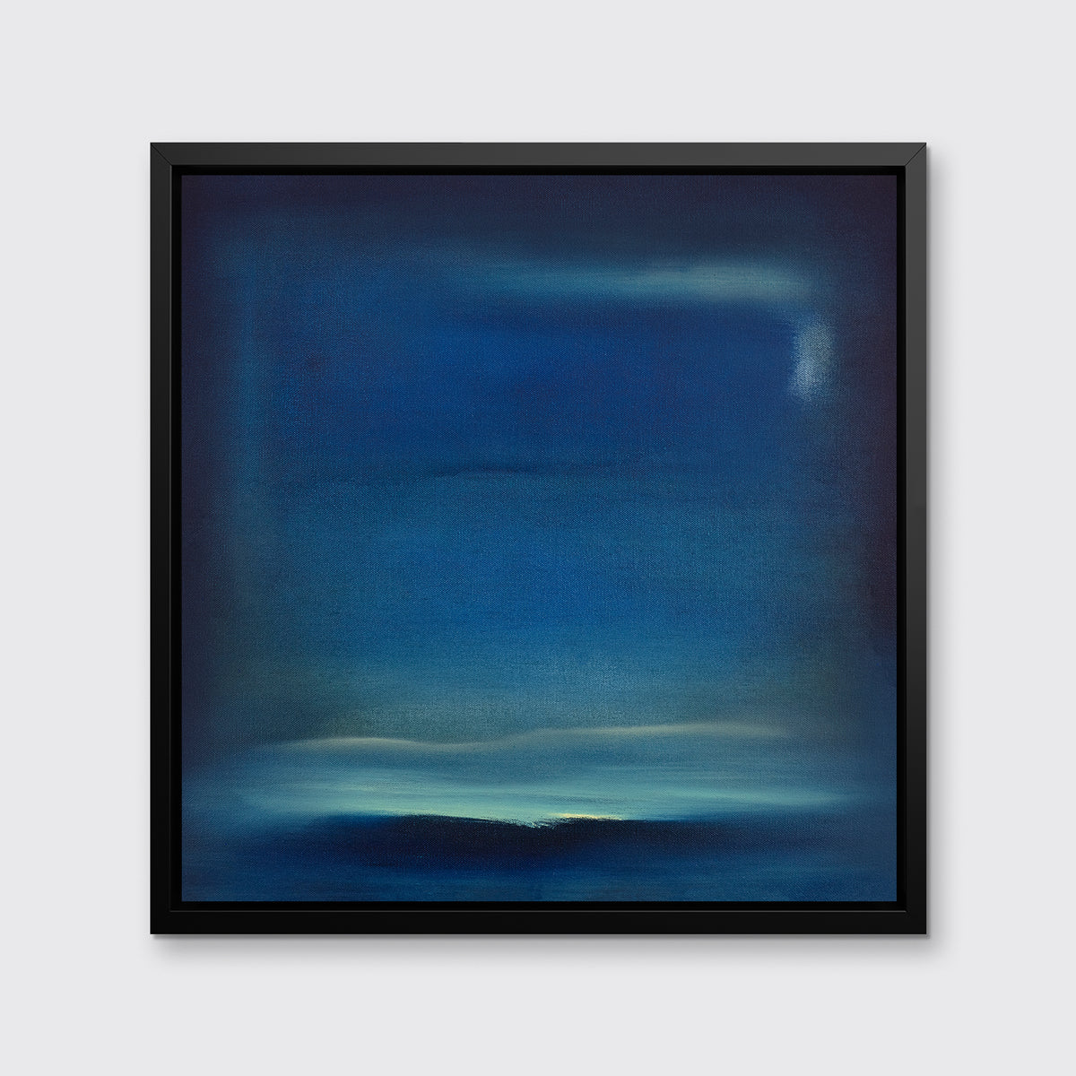 A dark blue and teal with accents of light yellow abstract print in a black floater frame hangs on a white wall.