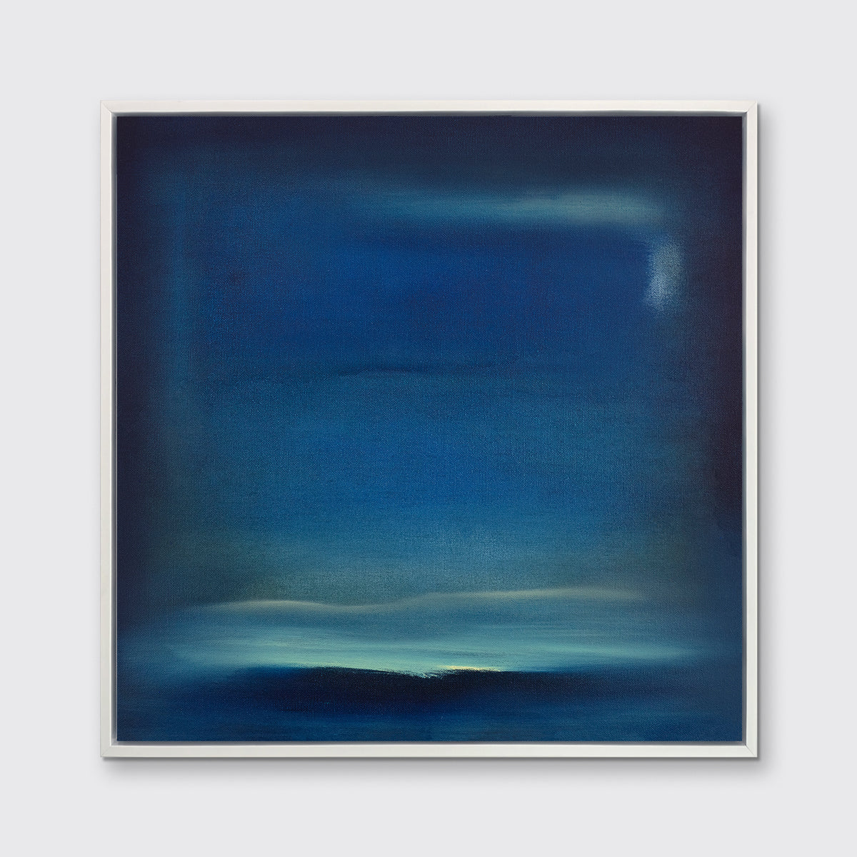 A dark blue and teal with accents of light yellow abstract print in a white floater frame hangs on a white wall.