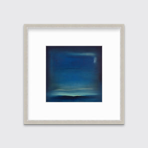A dark blue and teal with accents of light yellow abstract print in a silver frame with a mat hangs on a white wall.
